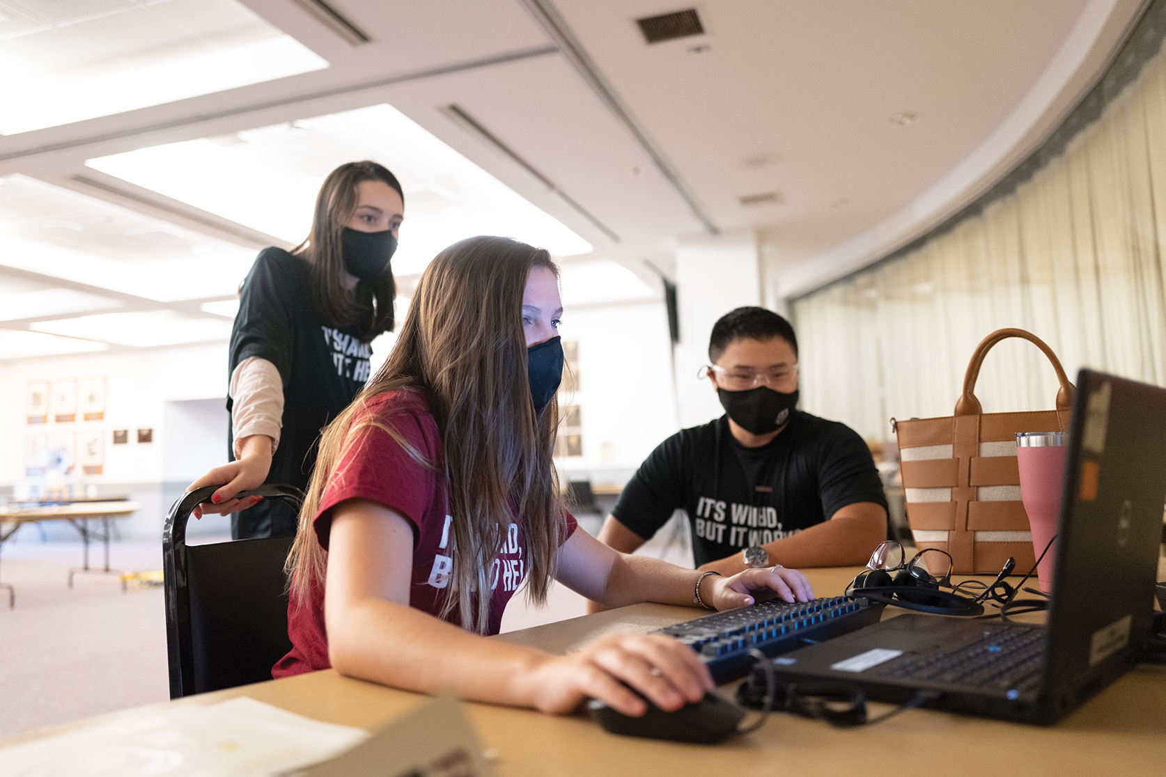 Students wearing masks work on a computer together
