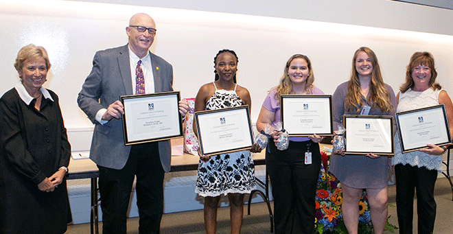 (from left) Dean Vitello presents the GSN Interprofessional Community Service Award to Vaccine Corps members Michael Hirsh, MD; Monica Mbugua; Helen Tsiagras; Emily Everett; and Jill Terrien, PhD.