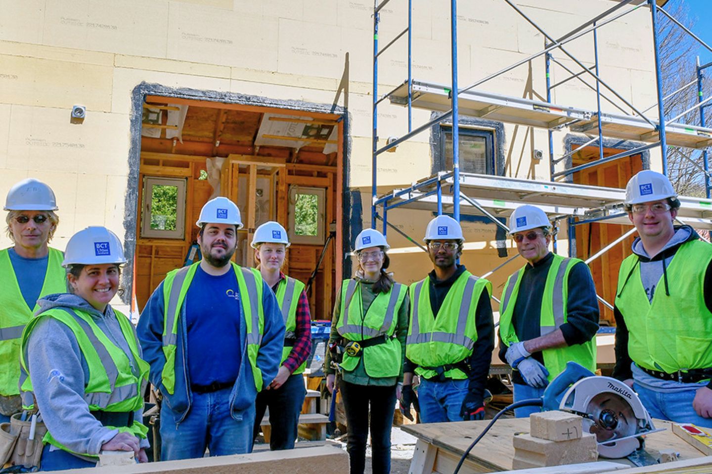 Construction workers posing for a picture in front of a renovated UMass building. 