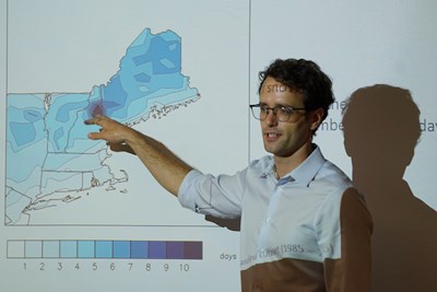 Assistant Professor Christopher Skinner points at a map on a white board
