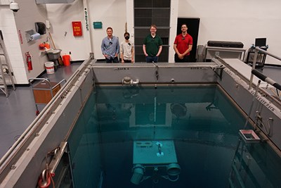 Assistant Professor Marian Jandel stands with Ph.D. student Alex Howe, rising senior Michael McGlynn and Ph.D. student Razvan Stanescu at one end of the pool located inside the nuclear reactor.
