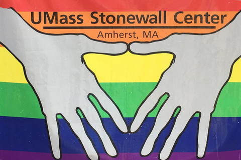 Artwork for UMass Stonewall Center of two hands forming a heart over a rainbow flag