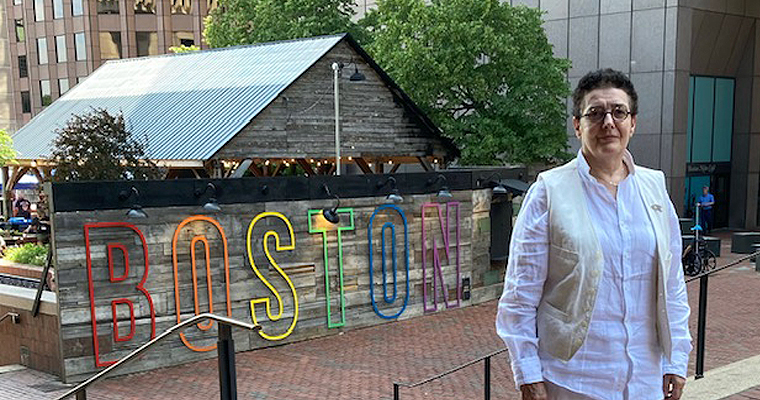 Reyes Coll-Tellechea stands in front of a rainbow sign that says "Boston"