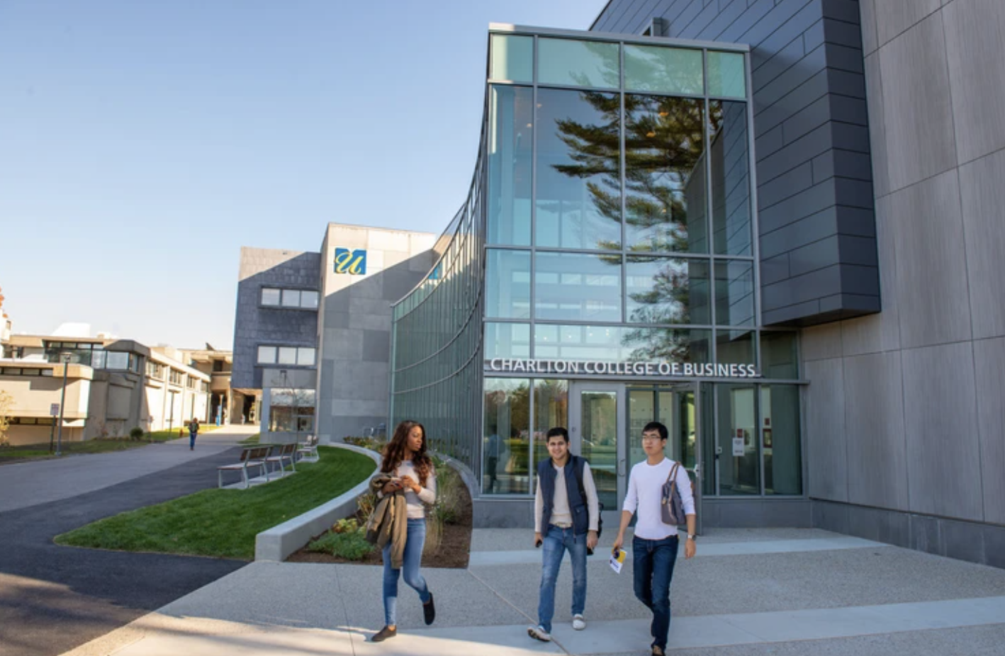 Three students walk out of Charlton College of Business building on UMass Dartmouth campus