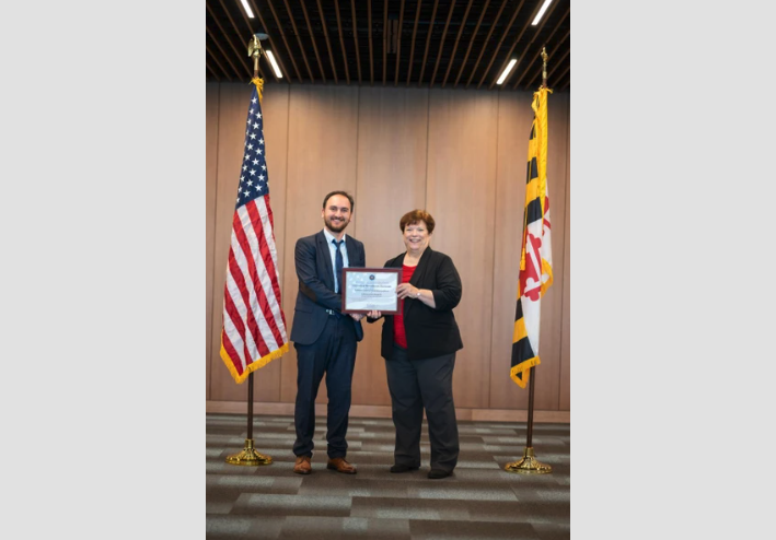 Gokhan Kul accepting the designation certificate of National Center of Academic Excellence in Cybersecurity - Research presented by Lynne Clark from the National Security Agency on April 25, 2022 at the U.S. Naval Academy. (Photo courtesy of G. Kul.)