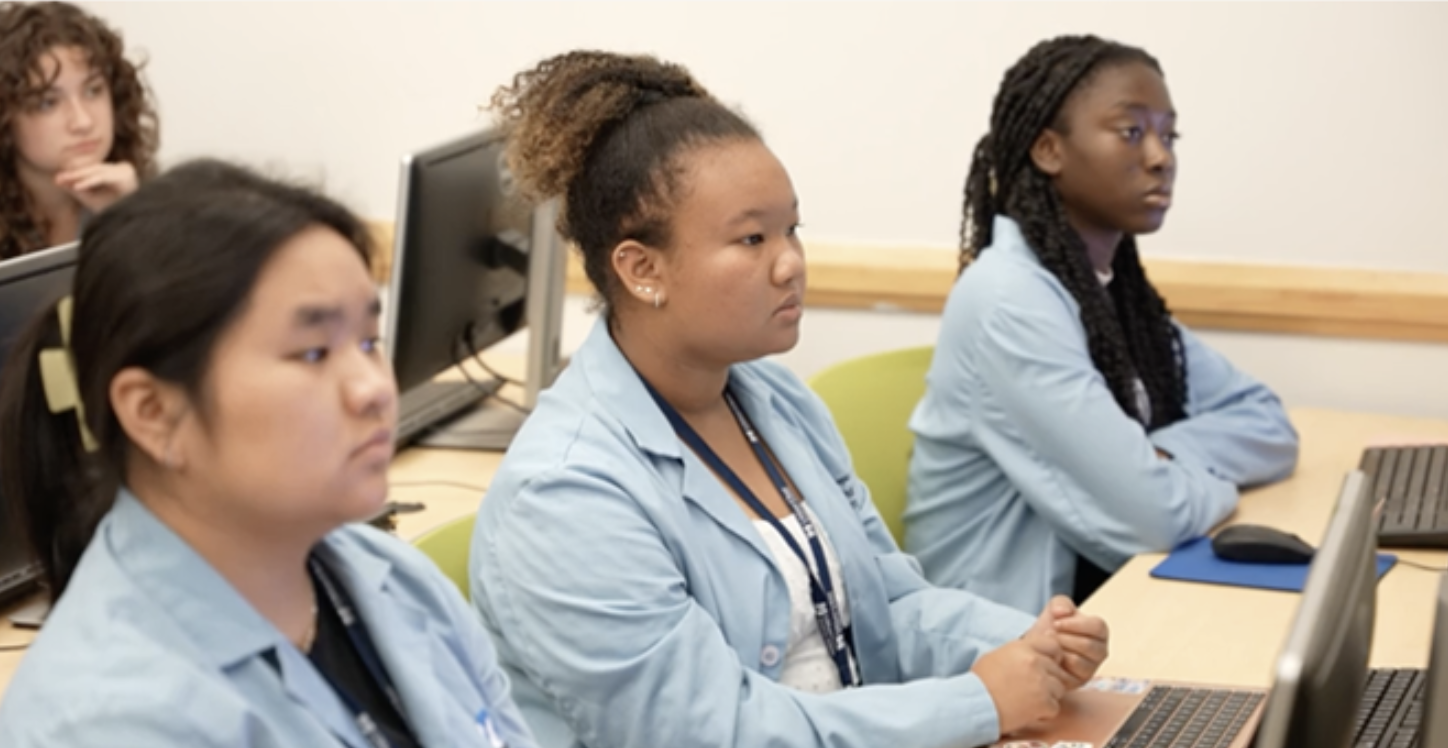 Students participating in the High School Health Careers Program are provided a blue lab coat to wear for the entirety of the summer program. Back row: Amalia Rodrigues; Front row (L to R): Julianne Chau, Marie Niane and Glory Adu-Gyamfi