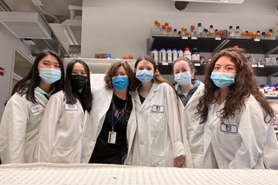 Professor Shannon Kelleher, in black top, with applied biomedical sciences majors, from left, Stendy Ly, SreyNich Song, Jessica Ross, Kaitlin Cronin and Angelly Peralta stand in lab with masks on