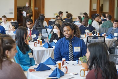 Symposium attendees sit at tables and talk to each other during event