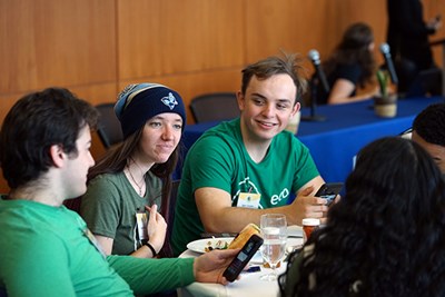 Three students sit at a table and talk to each other during event