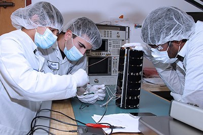 From left: SPACE HAUC program manager Sanjeev Mehta ’18, mechanical engineering sophomore Nicholas Carnes and physics Ph.D. student Sunip Mukherjee check the satellite’s electronics inside the clean room facility of the Lowell Center for Space Science and Technology (LoCSST) near East Campus following the pre-launch vibration test in June.