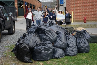 Society of Environmental Scientists members Fiona Benzi, Andrew Riggs, Jamie-Lyn Cavallon, Thomas Furtado, Sarah Mahannah and Lucia Cheney pose behind the trash they collected alongside Lowell Litter Krewe and Lowell's Life Connection Center.