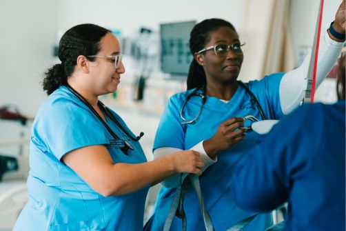 UMass Boston nursing students working in a lab environment with scrubs on. 