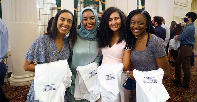 At the White Coat Ceremony last fall, T.H. Chan School of Medicine Class of 2024 students (from left), Jordan Dudley, Weaam Arman, Natalie Sorial and Kassandra Jean-Marie pose for a photo.