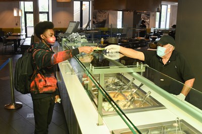 A University Dining staff member serves a student a salad during lunch at Fox Dining Commons.