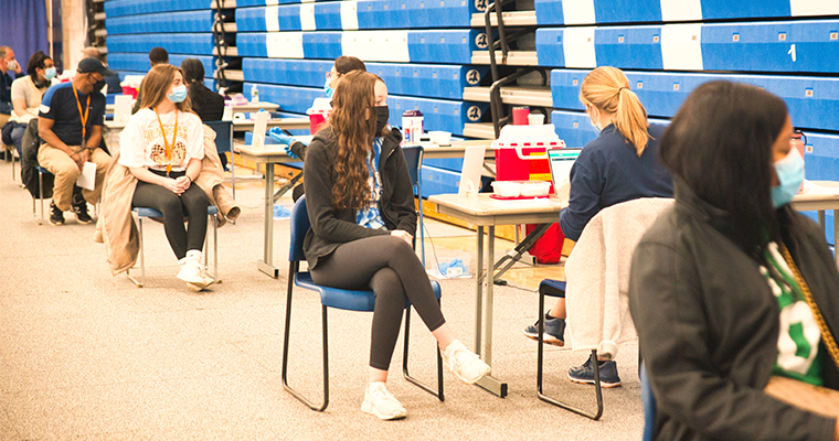 Students sit in gym waiting for vaccinations