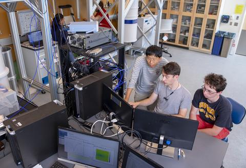 Three students work on a computer in the engineering lab