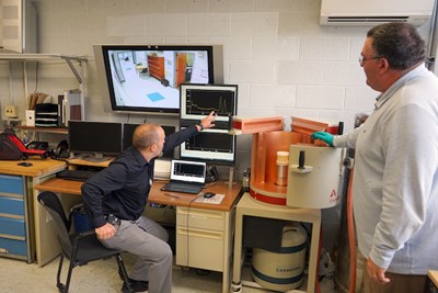 Director of Radiation Safety Steven Snay, left, shows how a gamma spectrometer works while Christopher Tavares looks on at Pinanski Hall.
