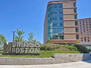 UMass Boston residence hall from the ground floor outside in front of the UMass Boston logo. 