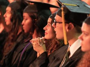 UMass students sitting down at graduation awaiting to receive their diplomas.