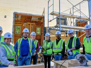 Group of construction workers standing at a site smiling at the camera.