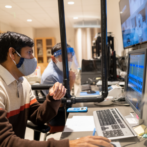 UMass researchers who are wearing facemasks working on computers