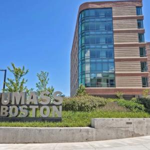 UMass Boston residence hall from the ground floor outside in front of the UMass Boston logo. 