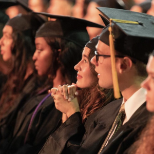 UMass students sitting down at graduation awaiting to receive their diplomas.