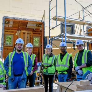 Group of construction workers standing at a site smiling at the camera.
