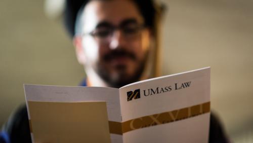 UMass Law graduate reading a commencement pamphlet