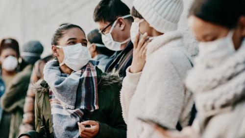 Students wearing masks wait in line outside