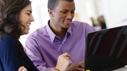 Two students work on a laptop together