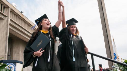 Two excited female students at UMass Dartmouth commencement