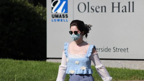 Student walks on campus while wearing a mask