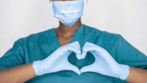A healthcare worker makes a heart hand gesture