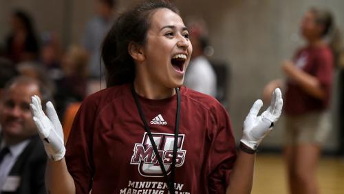 Student wearing a UMass Amherst Minuteman Marching Band shirt and chanting.