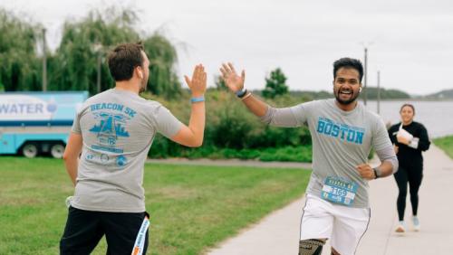 Two students running past each other and giving a high five.