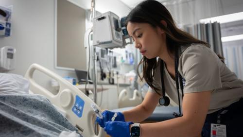 Healthcare worker caring for a patient in a hospital room.